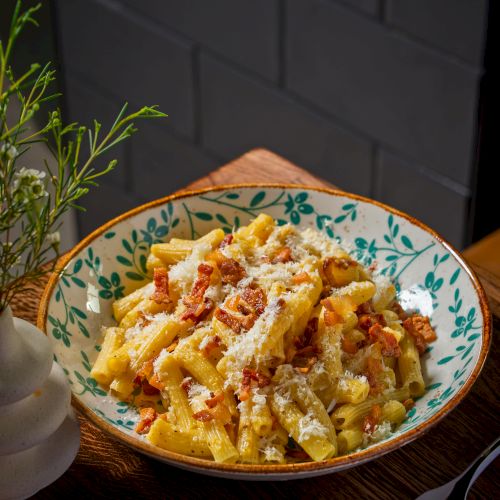 A colorful plate of pasta topped with cheese and herbs, served in a blue patterned bowl. Top it at 140 characters, always ending the sentence.
